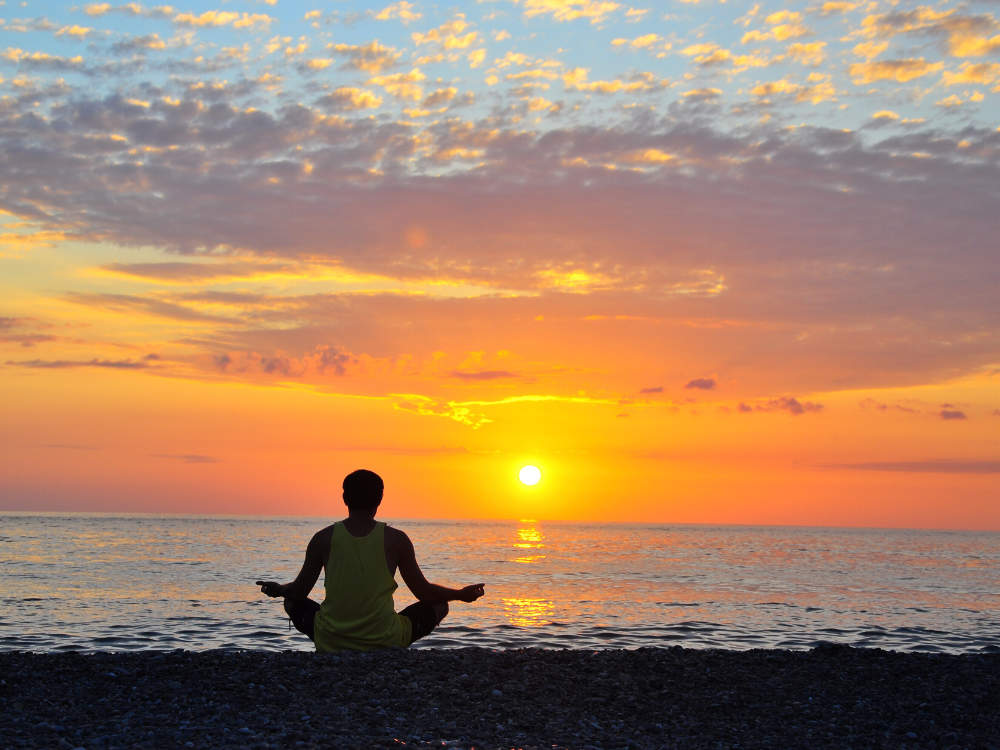 Meditating at water with sunset